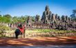 angkor wat temple from across the pond, with tourists on an elephant ride in foreground