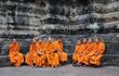 monks in traditional orange robes sitting on a temple wall