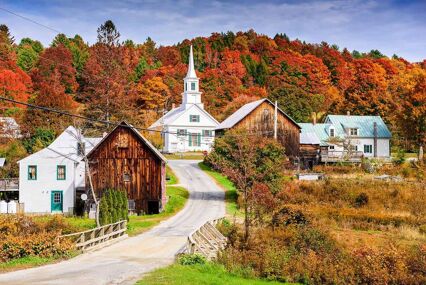 landscape of pretty new england buildings with fiery coloured trees in background
