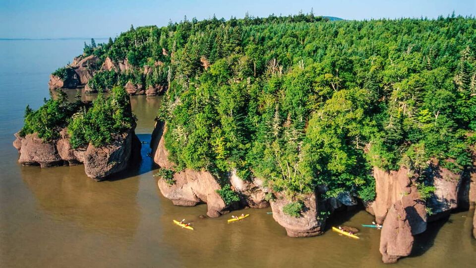 big cliffs and rocks with small kayaks paddling around them