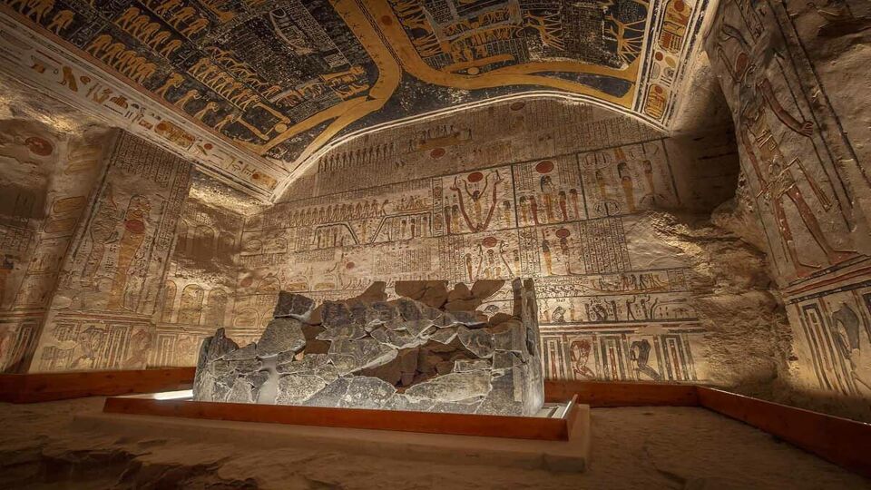 Broken pieces of the coffin set in a vaulted room covered in hieroglyphs