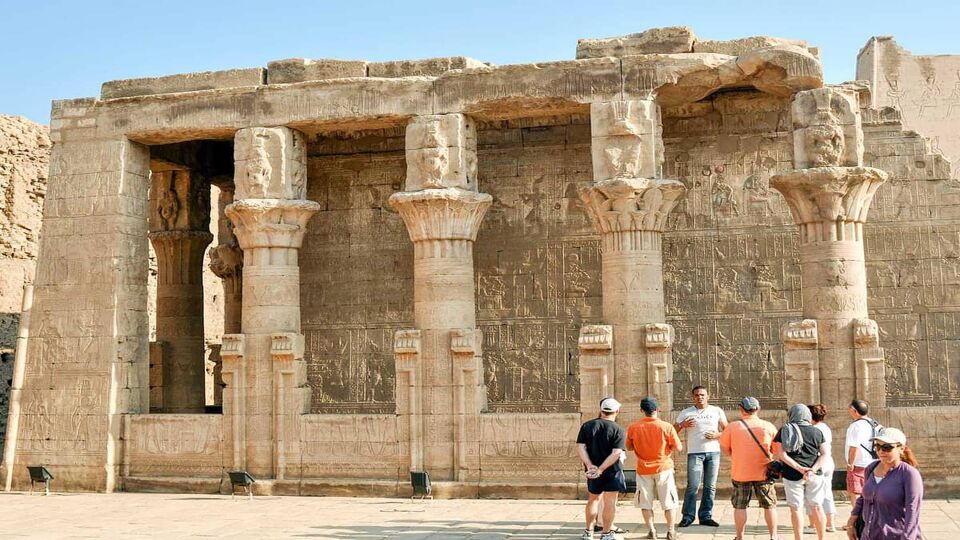 group of tourists standing before the large columns of the temple