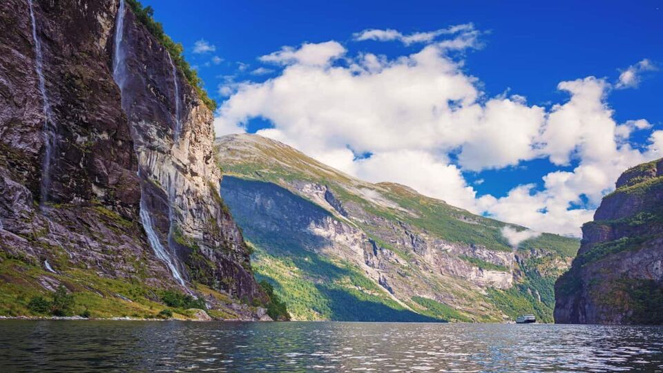 View of Geiranger fjord from the water, with waterfall off to the side