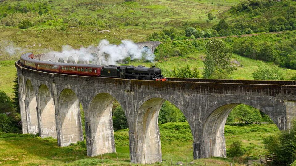 steam train passing over an arched stone viaduct