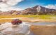 vehicle driving through a stream on a vast empty plain