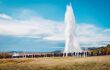 geysir erupting a fountain of water into the sky in front of lots of onlookers