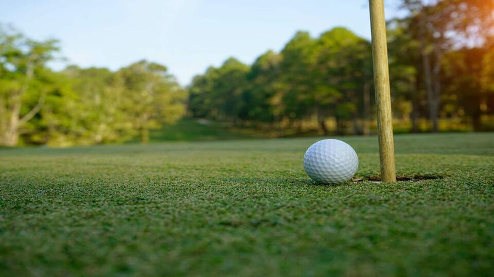 Golf ball on green in the evening golf course with sunshine