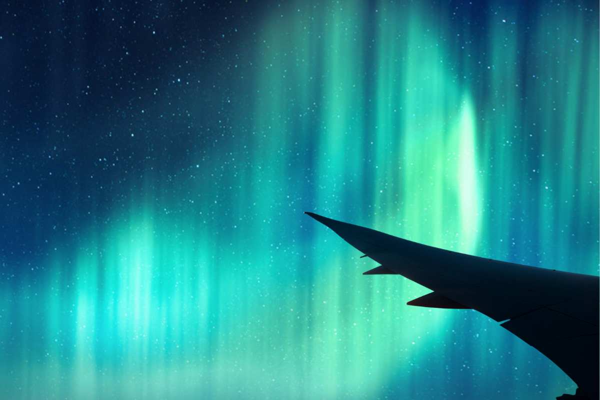 Boeing plane in flight with Northern Lights behind