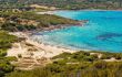 Holidaymakers in the crystal clear turquoise Mediterranean sea at Bodri beach in the Balagne region of Corsica with railway line and maquis in the foreground and deep blue sky