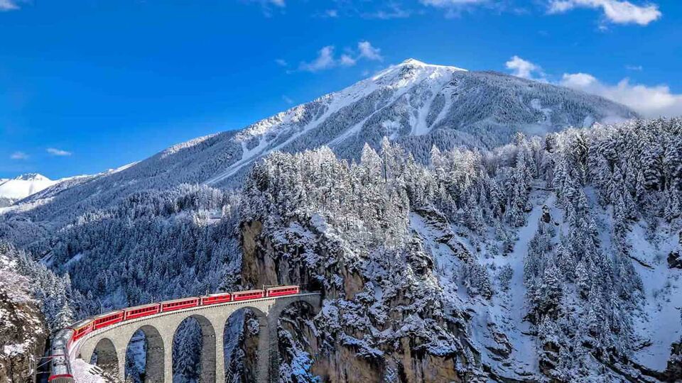Glacier Express train going into a tunnel in mountains