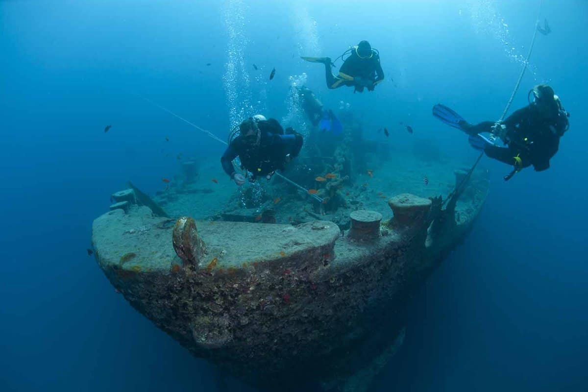 Silhouettes of scuba divers exploring the bow of the SS Thistlegorm shipwreck. SS Thistlegorm, Straights of Gubal, Red Sea, Egypt.