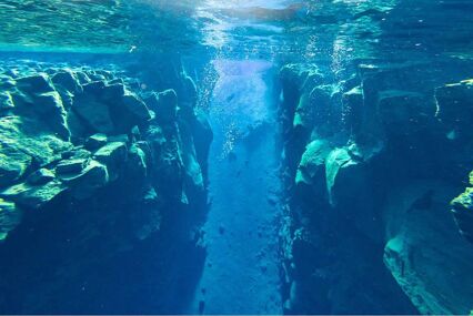 Underwater view of divers in the clear water between the tetonic plates of the Silfa Rift