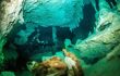 Divers swimming through the underwater caverns of Cenote Dos Ojos