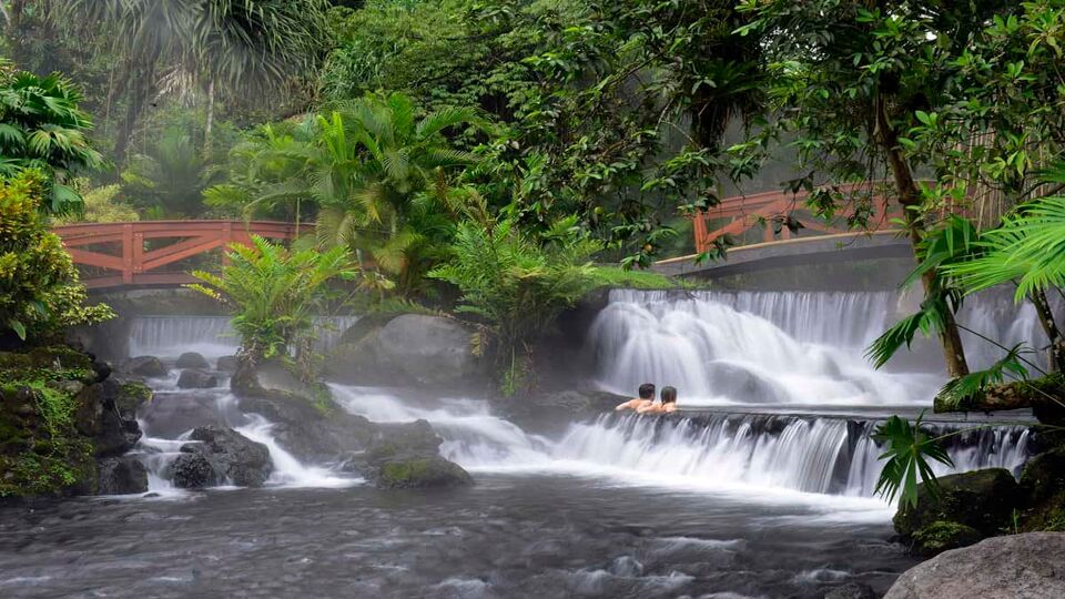 couple relaxing on the cascading hot springs of the natural spa